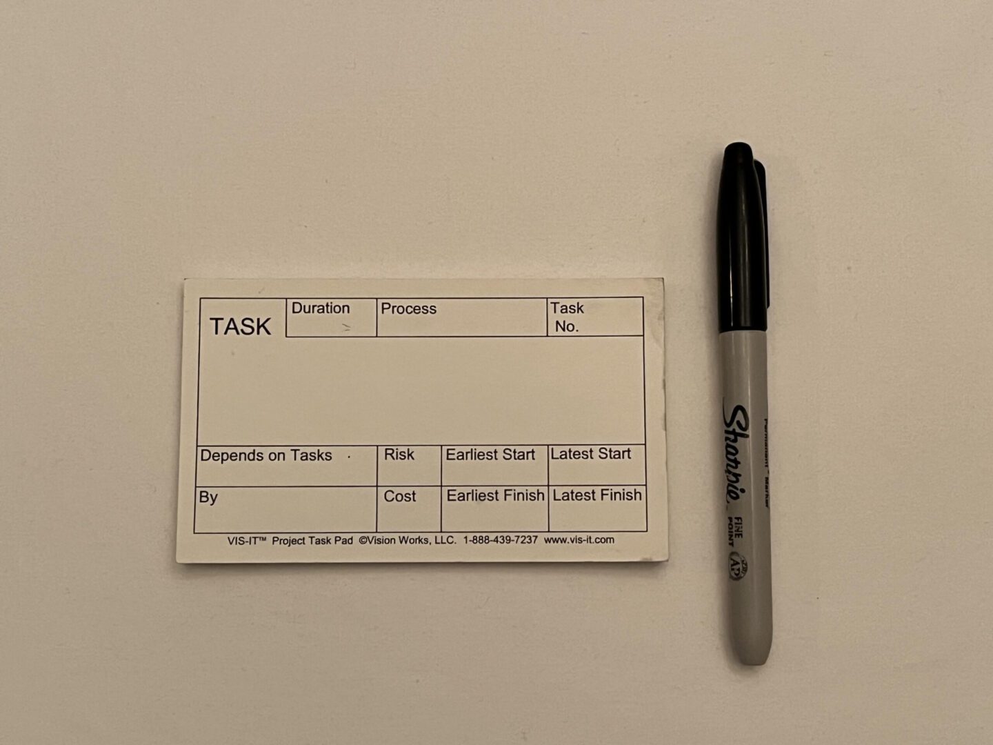 A white VIS-IT™ Small Project Task Pad 5x3 in. (50 sheets) with a pen next to it.